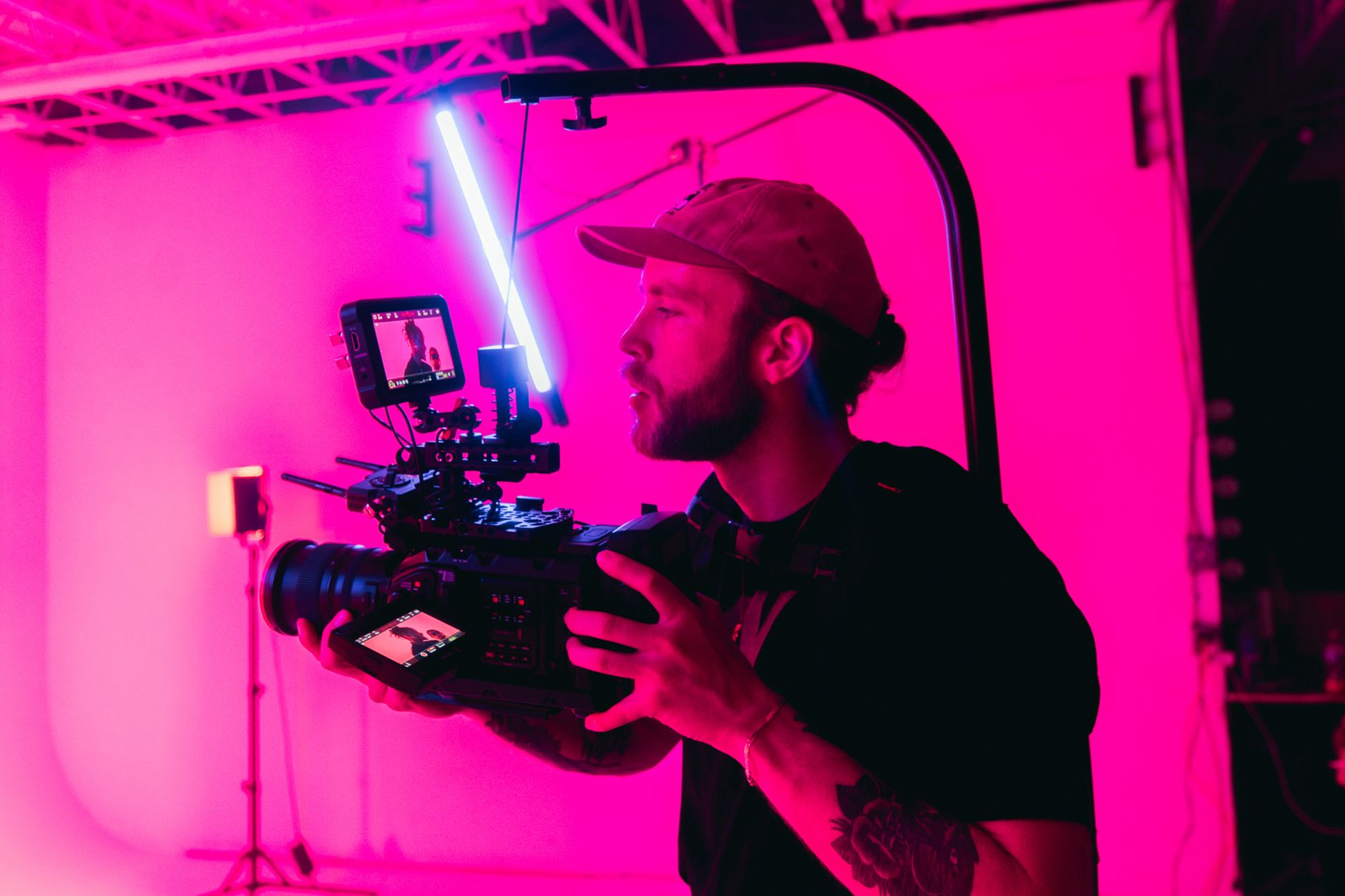 A creator filming content with a professional camera in a neon-lit studio.